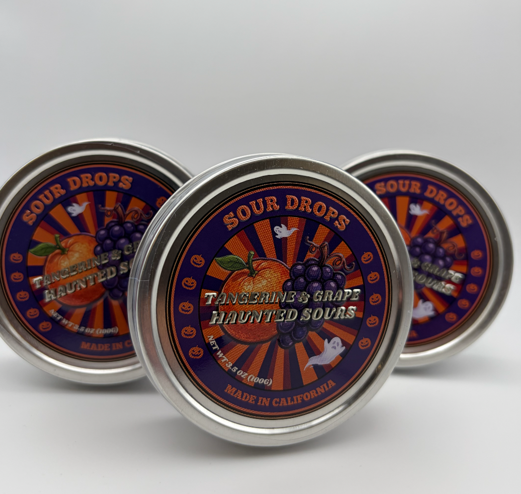 Three Tangerine & Grape Haunted Sours tins with Halloween artwork of a tangerine, grapes, ghosts and pumpkins
