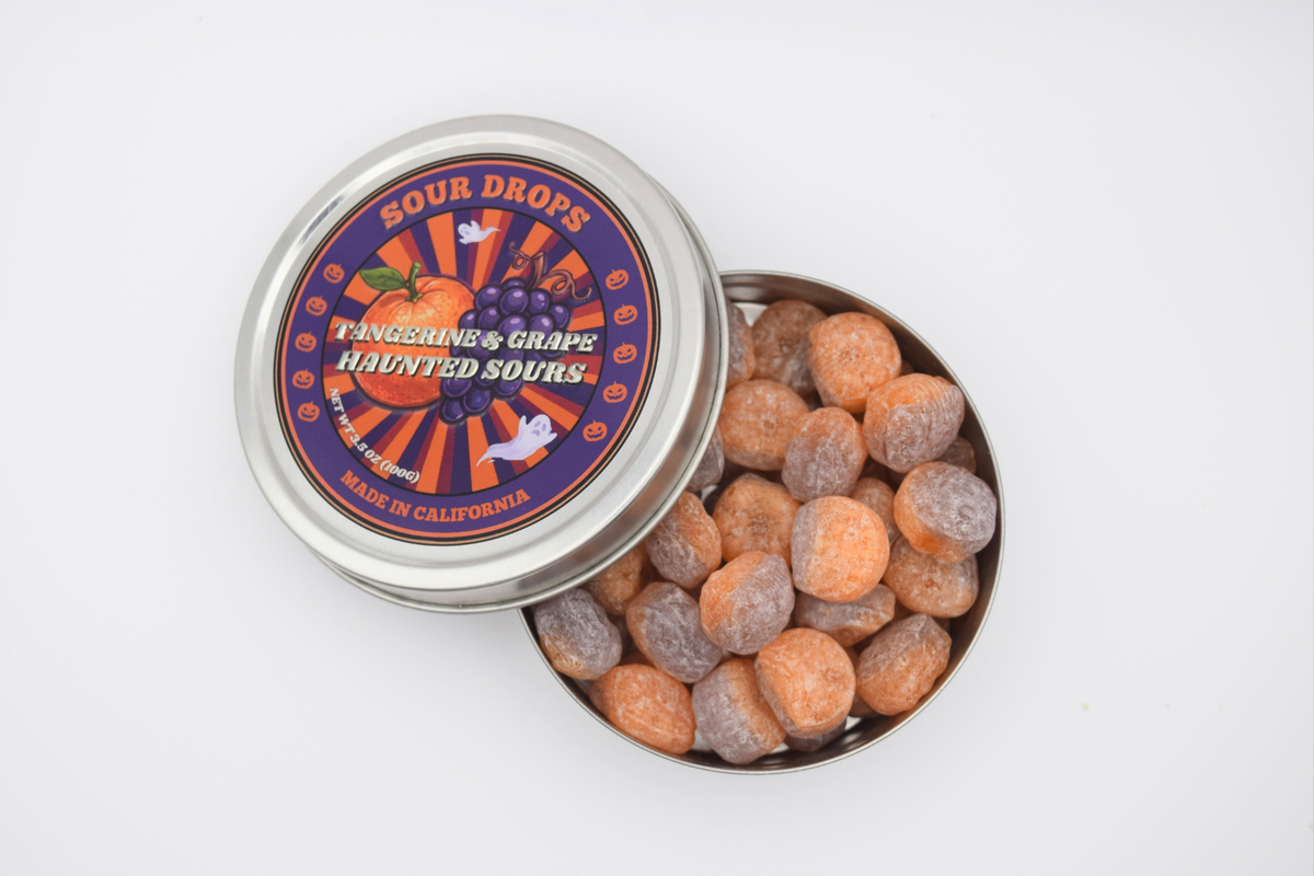 Open tin of Tangerine & Grape Haunted Sours Fusions showing the half-orange, half-purple sour candy drops inside
